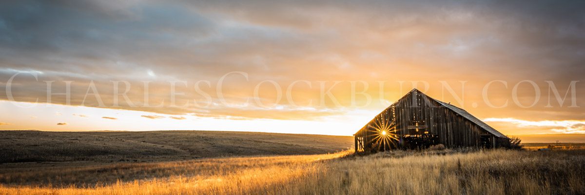 The setting sun sparkles through the crumbling wood of an ancient barn on the prairie near Douglas, Washington | CharlesCockburn.com